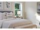 Bright bedroom features a cozy bed with decorative pillows and a bench, complemented by natural light from the window at 956 Harbor Town Dr, Venice, FL 34292