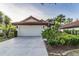 Beautiful front exterior showing a two-car garage, and manicured tropical landscaping at 956 Harbor Town Dr, Venice, FL 34292