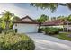 Front exterior showing a two-car garage, and meticulously maintained tropical landscaping at 956 Harbor Town Dr, Venice, FL 34292