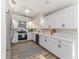Modern kitchen with white cabinets, stainless steel appliances, light backsplash and wood floors at 956 Harbor Town Dr, Venice, FL 34292
