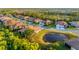 Scenic aerial view of homes nestled around a pond, with mature trees in the background at 2765 Arugula Dr, North Port, FL 34289