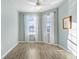 Bedroom with wood-look flooring, two windows with blinds and sheer white curtains and a ceiling fan at 2765 Arugula Dr, North Port, FL 34289