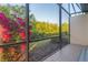 View from a screened-in porch, with lush foliage and bright pink blooms at 2765 Arugula Dr, North Port, FL 34289