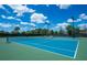 Bright blue tennis courts with lush green surroundings, under a sky with puffy clouds and sunny skies at 2765 Arugula Dr, North Port, FL 34289