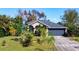 Charming home with a gray roof, arched entryways, complemented by lush palm trees and green landscaping at 3316 Kacher Rd, North Port, FL 34288