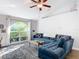 Bright living room featuring a large arched window, plush blue sectional sofa, and a ceiling fan at 3316 Kacher Rd, North Port, FL 34288