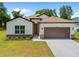 The house featuring a lawn, dark roof, and a neutral exterior paint scheme with stone accents at 3390 Nadasky Ave, North Port, FL 34288
