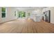 Bright open living room showcasing wood-look flooring and a seamless transition to the kitchen with natural light at 3390 Nadasky Ave, North Port, FL 34288
