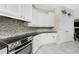 Modern kitchen with white cabinetry, stone backsplash and stainless steel appliances at 1945 Jamaica Way, Punta Gorda, FL 33950