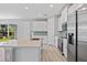Bright kitchen with white cabinets, stainless steel appliances, an island and light blue backsplash at 1301 Preston St, Port Charlotte, FL 33952