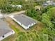Aerial view of white single story home with gray roof, green trees, and grassy yard at 2643 Rushmore St, North Port, FL 34288