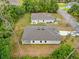Aerial view of a single-story home with a light gray roof, a long driveway, and green trees at 2643 Rushmore St, North Port, FL 34288