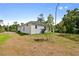 Image of the backyard featuring a white house, green trees, grass, and blue water tanks at 2643 Rushmore St, North Port, FL 34288