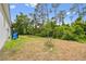 Image of the backyard featuring a white house, green trees, grass, and blue water tanks at 2643 Rushmore St, North Port, FL 34288