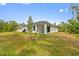 Image of the backyard featuring a white house, green trees, grass, and a cozy patio at 2643 Rushmore St, North Port, FL 34288