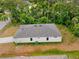 Side aerial view of white single story home with gray roof, green trees, and grassy yard at 2643 Rushmore St, North Port, FL 34288