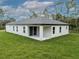 Back view of a single-story home showcasing the patio with a large lawn, bright exterior and natural setting at 3705 Baynes Rd, North Port, FL 34288