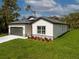Low angle view of a single-story home, manicured lawn, and gray two-car garage with a dark roof at 3705 Baynes Rd, North Port, FL 34288