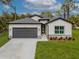 Charming single-story home with a well-manicured lawn, gray two-car garage, and tastefully landscaped front yard at 3705 Baynes Rd, North Port, FL 34288