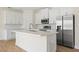A kitchen features white cabinetry, stainless steel appliances, and an island with a sink at 3779 Clearfield St, North Port, FL 34286