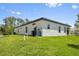 Side view of home's exterior showing modern architecture, well-maintained lawn, and utility connections at 3802 Eagle Pass St, North Port, FL 34286