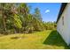 A wide shot of a home's backyard with a lush wooded perimeter and green lawn at 3883 Dominic St, North Port, FL 34288
