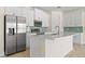 Bright kitchen features white cabinets, stainless steel appliances, and a kitchen island with a white countertop at 3885 Eagle Pass St, North Port, FL 34286