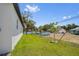 The expansive, green backyard showcases new trees, a white fence, and other homes in the neighborhood at 4131 Bula Ln, North Port, FL 34287
