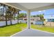 Outdoor patio offers relaxing shaded area surrounded by a green backyard, white fence and palm trees at 4131 Bula Ln, North Port, FL 34287