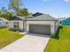 Front exterior of a charming single-Gathering home with a well-kept lawn and attached two car garage at 4131 Bula Ln, North Port, FL 34287
