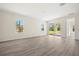 Bright living room with wood-look floors, neutral walls, and sliding glass doors to the patio at 1100 S Wapello St, North Port, FL 34286