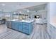 Open concept kitchen boasts a teal island, stainless steel appliances, and white cabinetry at 1450 Kiwi Ct, Punta Gorda, FL 33950