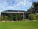 Screened patio with lush tropical landscaping and a red umbrella at 5101 Pine Shadow Ln, North Port, FL 34287