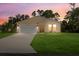 Attractive tan house with white garage doors, set against a twilight sky at 14220 Dunlap Ave, Port Charlotte, FL 33953