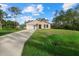 Tan house with a white garage door and a large green yard at 14220 Dunlap Ave, Port Charlotte, FL 33953