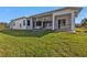 Exterior of home features a covered patio with a ceiling fan and green grass at 17152 Wintergarden Ave, Port Charlotte, FL 33948