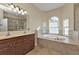 Serene bathroom with dual vanities, a soaking tub, a separate shower and natural light from the windows at 17152 Wintergarden Ave, Port Charlotte, FL 33948