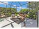 Relaxing screened patio with wicker furniture and lush landscaping at 2388 Silver Palm Rd, North Port, FL 34288