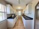 Galley kitchen with white appliances, cabinets, and tile floors with view to living area at 25068 Harborview Rd # 1A, Punta Gorda, FL 33980