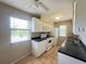 Charming kitchen featuring a window above the sink, white appliances and cabinets, and dark countertops at 25068 Harborview Rd # 1A, Punta Gorda, FL 33980