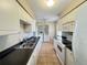 Galley kitchen featuring white cabinets, appliances, and tile floor with laundry area at 25068 Harborview Rd # 1A, Punta Gorda, FL 33980