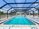 Screened-in swimming pool with an array of lounge chairs surrounded by well-maintained grounds at 25068 Harborview Rd # 1A, Punta Gorda, FL 33980