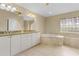 Elegant bathroom with double vanity, soaking tub, and a glass block window at 15460 Longview Rd, Port Charlotte, FL 33981