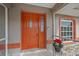 Inviting orange front door entryway with screened porch and poinsettia plant at 28522 Coco Palm Dr, Punta Gorda, FL 33982