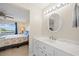 Clean bathroom with a white vanity, round mirror, and access to bedroom at 1512 Rio De Janeiro Ave # 111, Punta Gorda, FL 33983