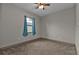 Spacious bedroom with carpeted floor, window with teal curtains, and ceiling fan at 19199 Roosevelt Ave, Port Charlotte, FL 33954