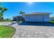 Gray house with paver driveway, two-car garage, and palm trees in front at 21341 Edgewater Dr, Port Charlotte, FL 33952