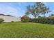 Backyard with lush landscaping, a privacy fence, and a large tree at 2246 Jasmine Way, North Port, FL 34287