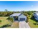 Single-story home with metal roof, driveway, and tropical landscaping at 17458 Fuego Ln, Punta Gorda, FL 33955