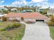An exterior elevation view of a single-story home featuring a tile roof, driveway and attached garage at 1923 Pennsylvania Ave, Englewood, FL 34224